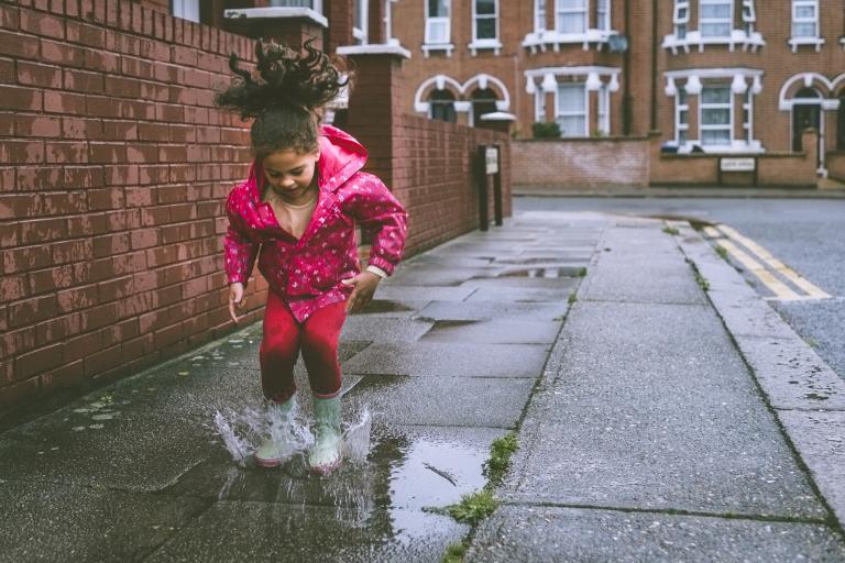 Little girl jumping and playing in a puddle