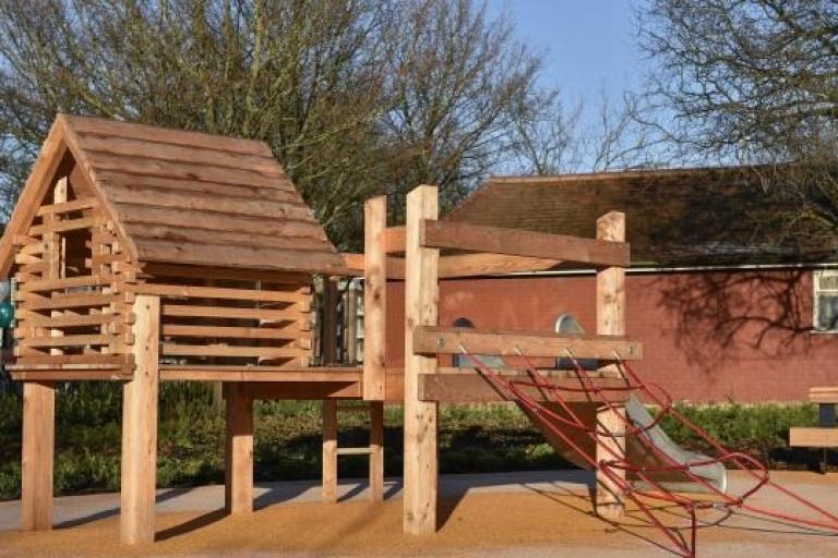 a wooden play house with a slide and rope climbing ladder 