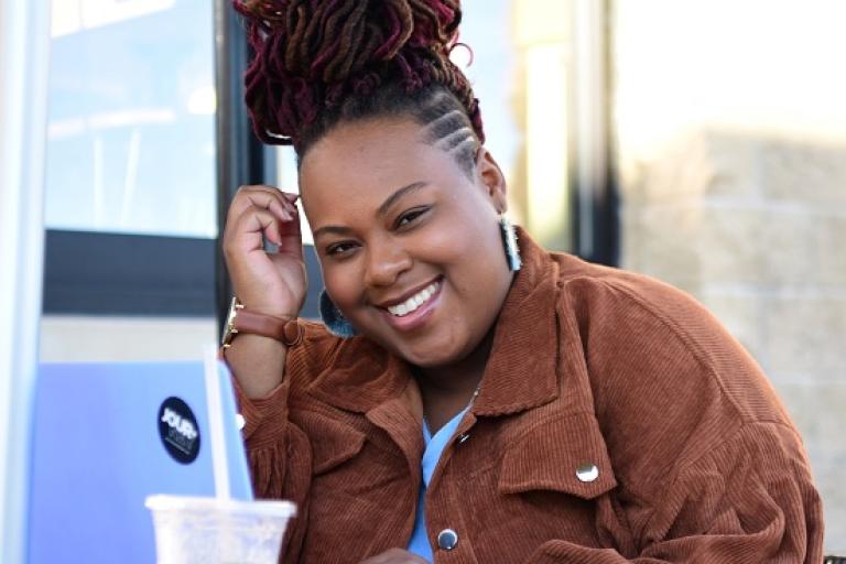 A young woman with a laptop smiling at the camera