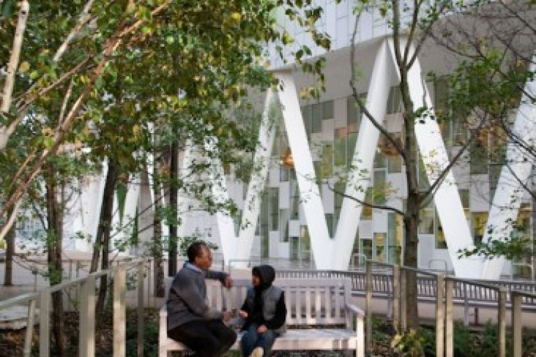 a parent and child on a bench surrounded by trees