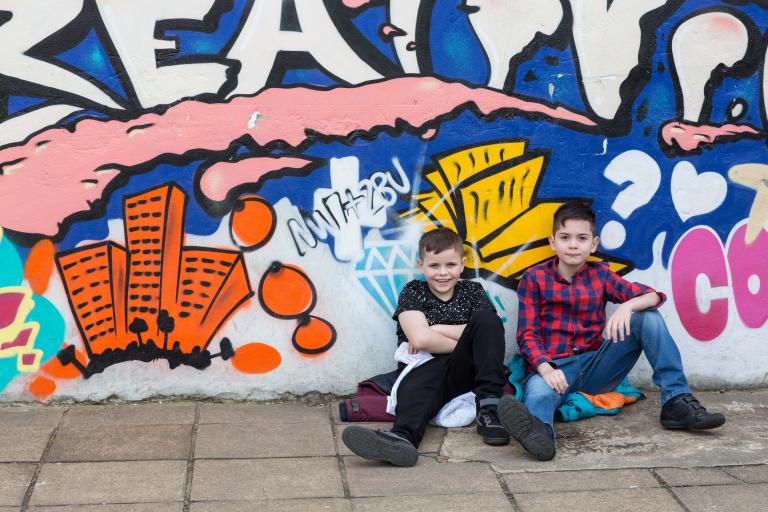 two boys smiling with art work in the background