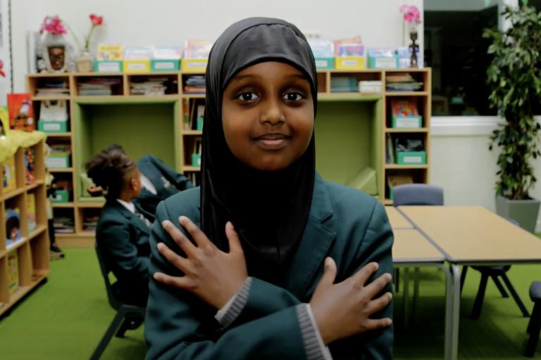 Girl crossing heart and smiling at camer