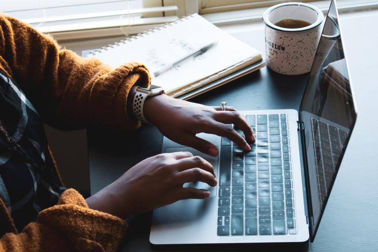 Woman at laptop with hot drink