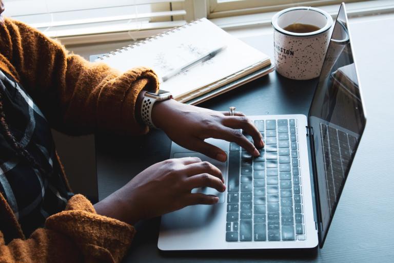 Woman at laptop with hot drink