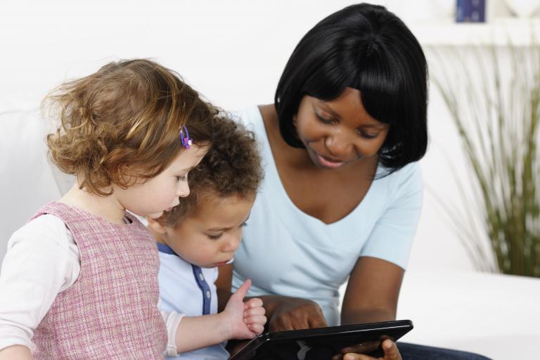 Woman with two children playing on tablet