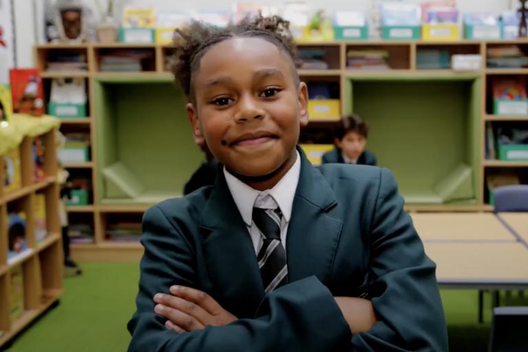 Boy in school uniform smiling with arms crossed