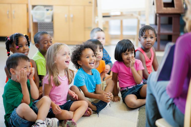 children-sitting-on-floor-listening-to-woman-reading