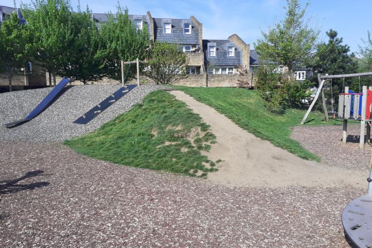 Image of a playground with slides and a swing