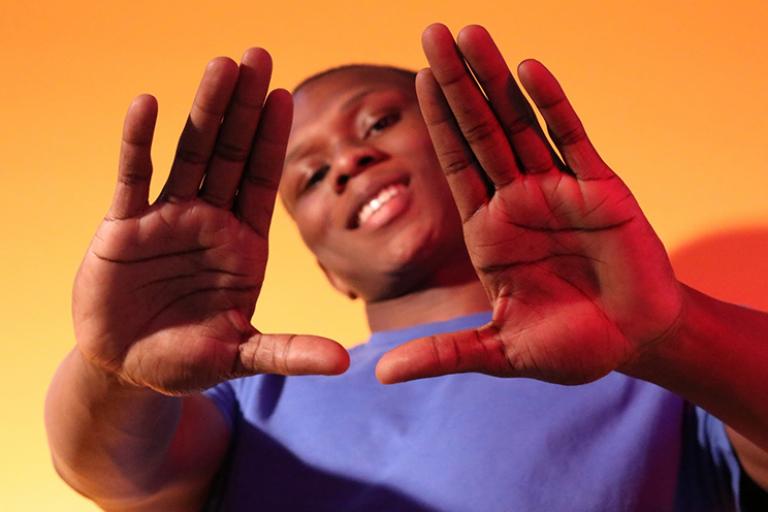 A young person framing their face for the camera with their palms
