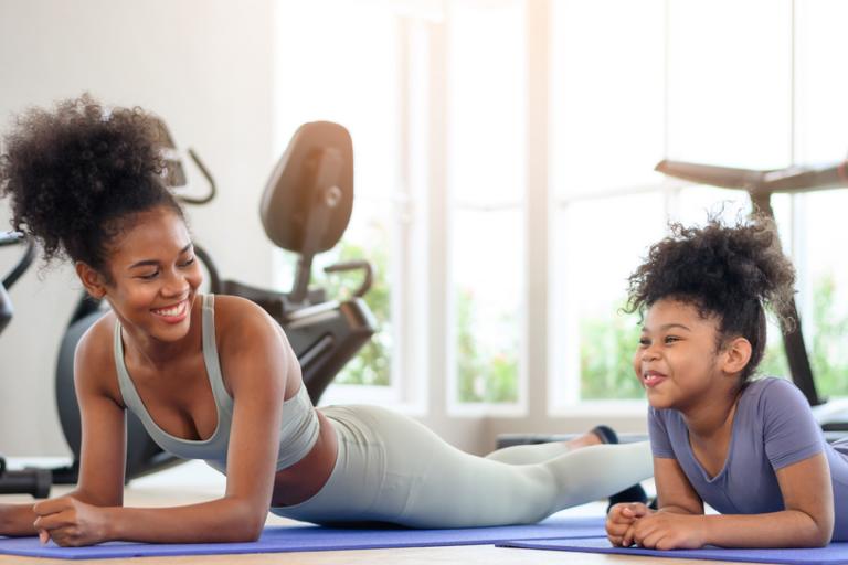 Adult and child exercising and laughing on mat