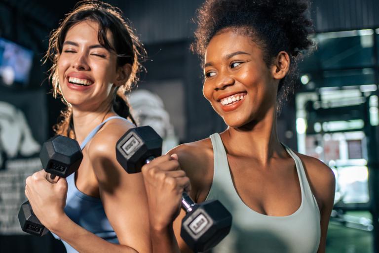 Two female friends working out with dumbbells