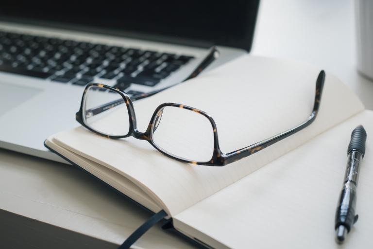 Laptop, notebook and glasses on a desktop