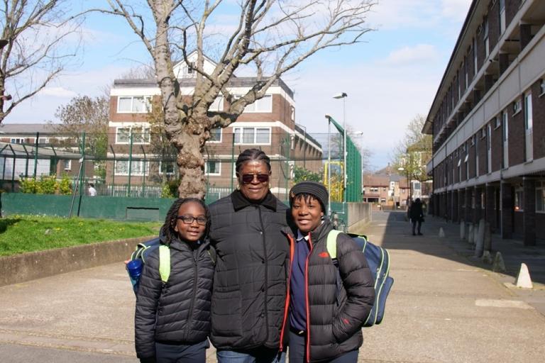 Mother and children standing by a sports area in an estate