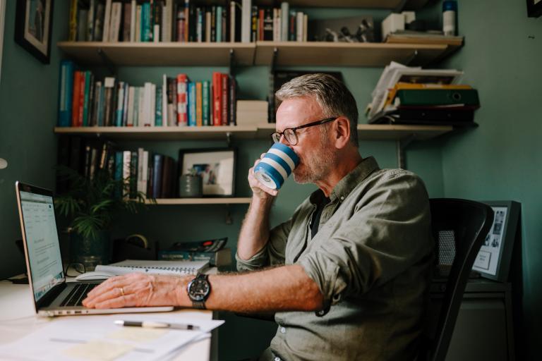 Man sitting with laptop drinking coffee