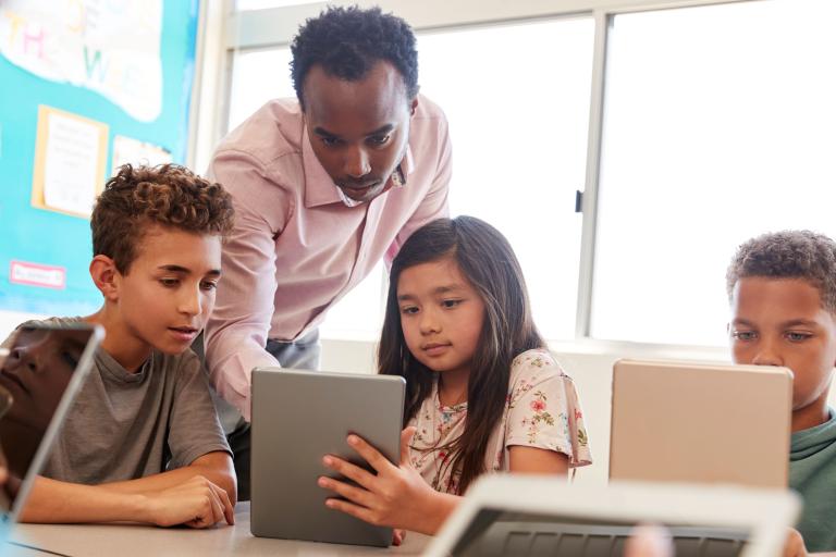 Man teaching children with tablets 