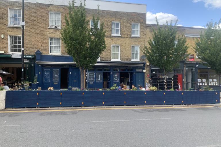 Blue wooden framed parklet with people dining outdoors