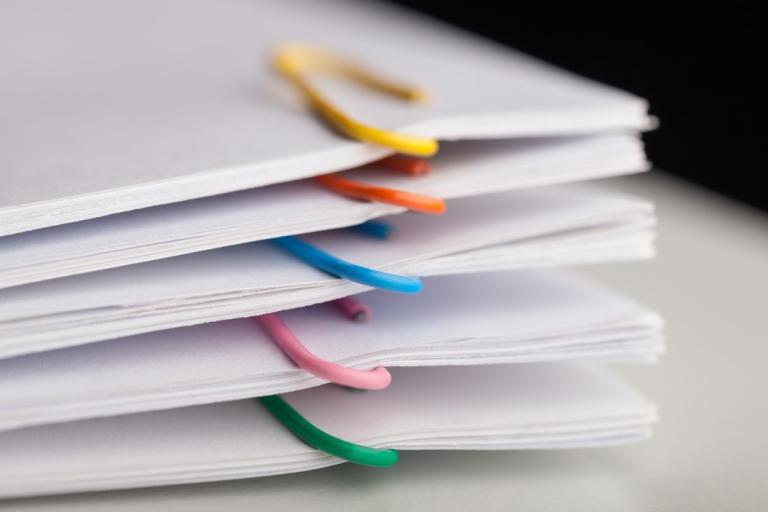 Pile of documents separated with colourful paperclips