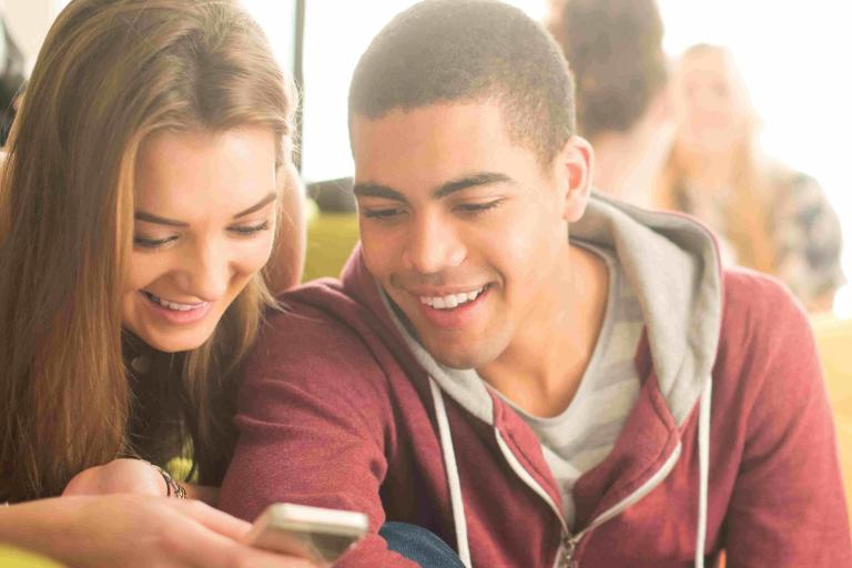 Two young people looking at a mobile phone