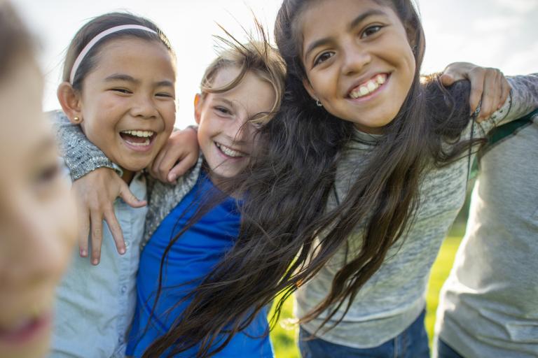 three children playing outdoors with smiling faces