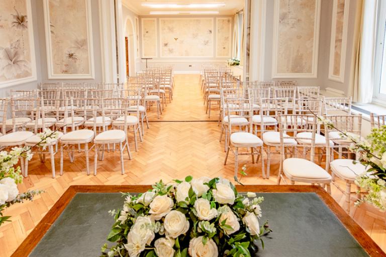Room with floral arrangement and chairs set up for a ceremony