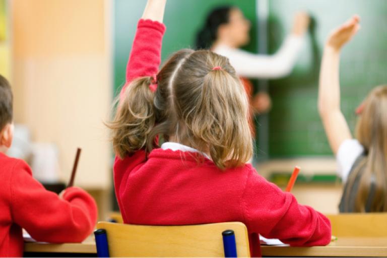 Pupils in classroom with hands up