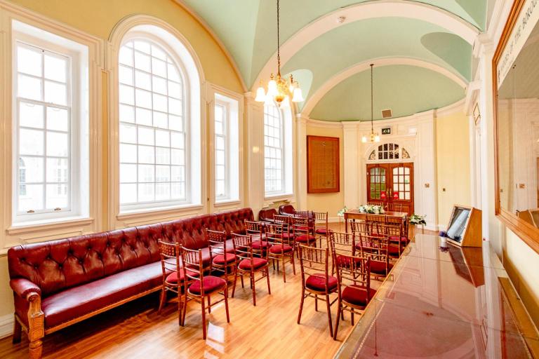 Wedding ceremony room at Lambeth Town Hall with rows of chairs, large arched windows and red upholstered seating.