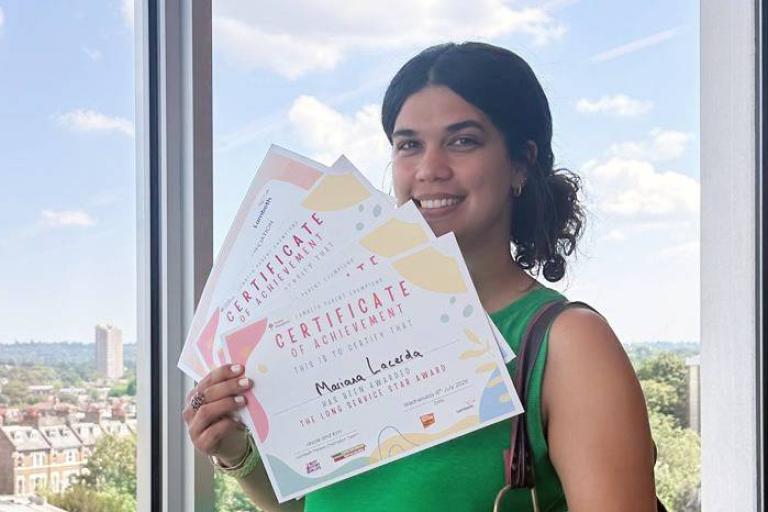 Mariana smiling and holding certificates