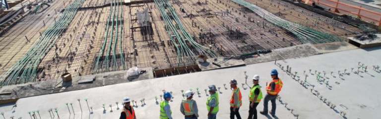 Construction workers standing on roof overlooking building construction site