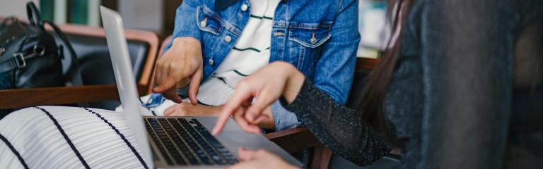 two women pointing at a laptop