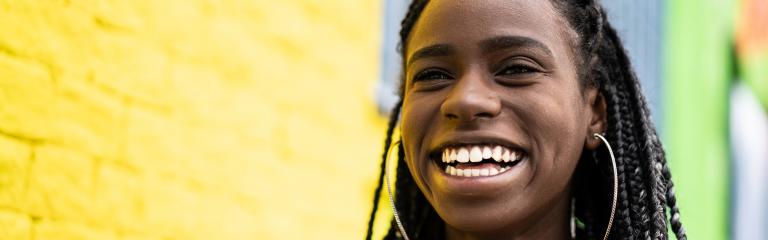 Young black woman laughing in vibrant coloured neighbourhood