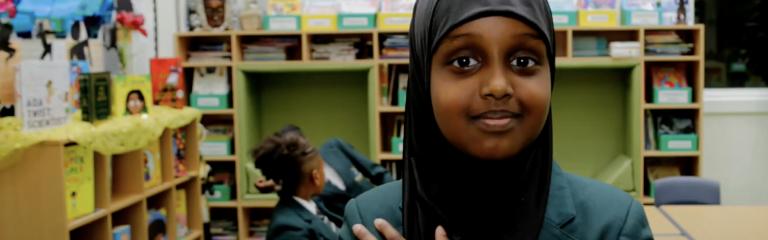 Girl crossing heart and smiling at camer