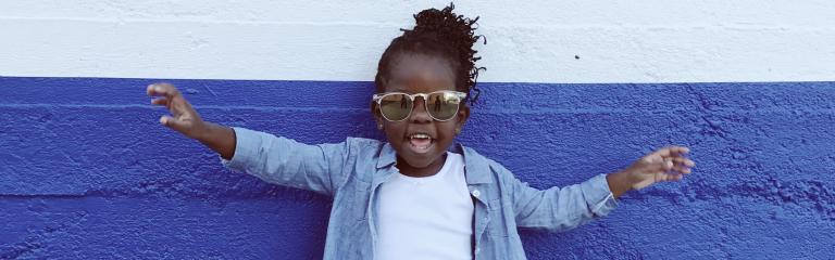Girl with sunglasses posing against the wall