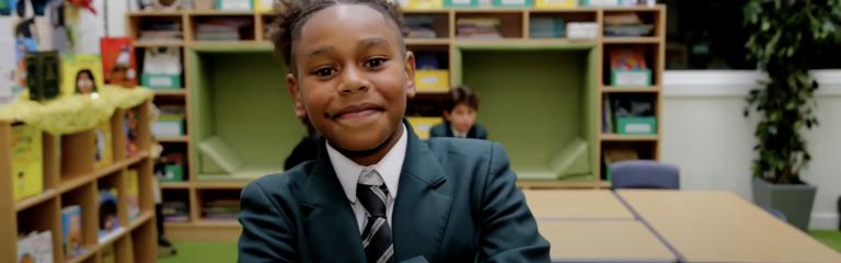 Boy in school uniform smiling with arms crossed