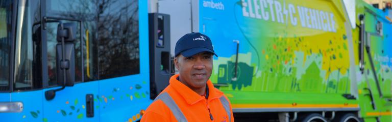 Picture of a waste & recycling crew member in front of an electric collection vehicle