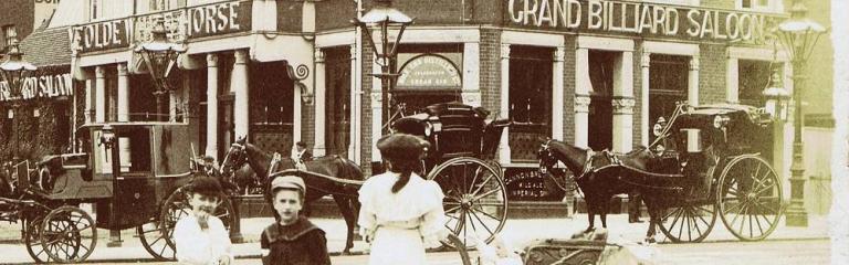 Vintage photo of a mother with a pram and two children standing across the road from a pub
