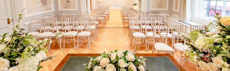 Room with floral arrangement and chairs set up for a ceremony