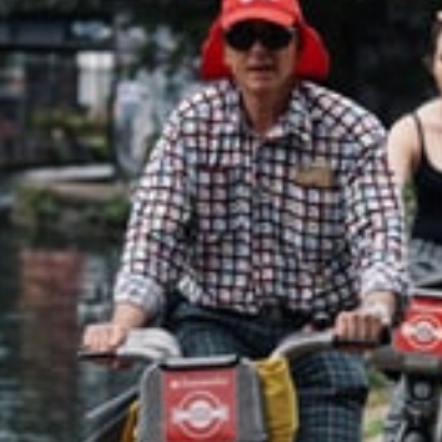 man and two women cycling on santander bikes in a row past a canal