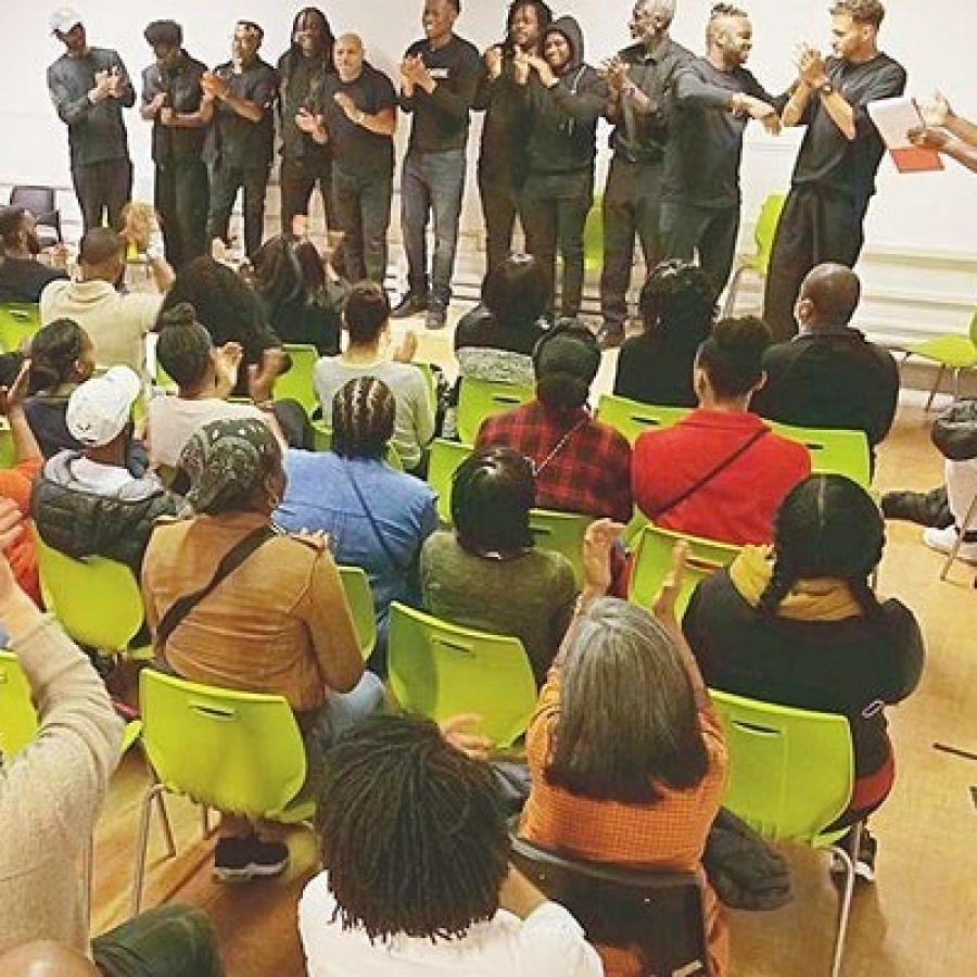 audience seated with performers on stage - black men's mental health project
