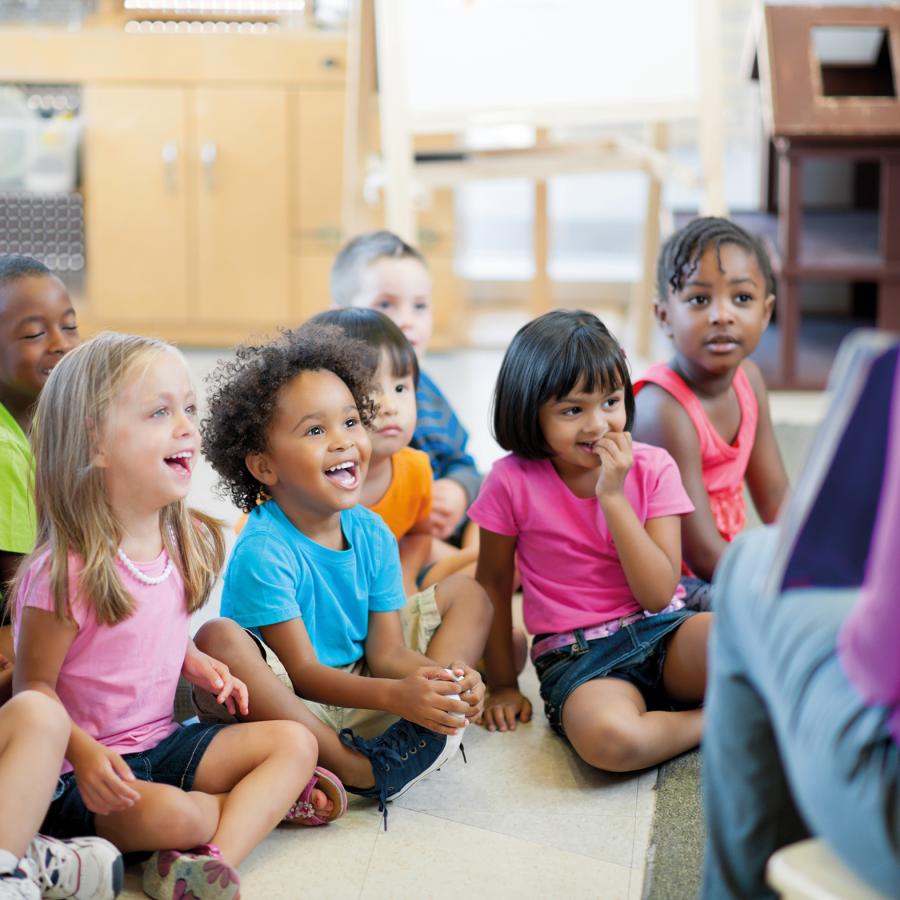 children-sitting-on-floor-listening-to-woman-reading