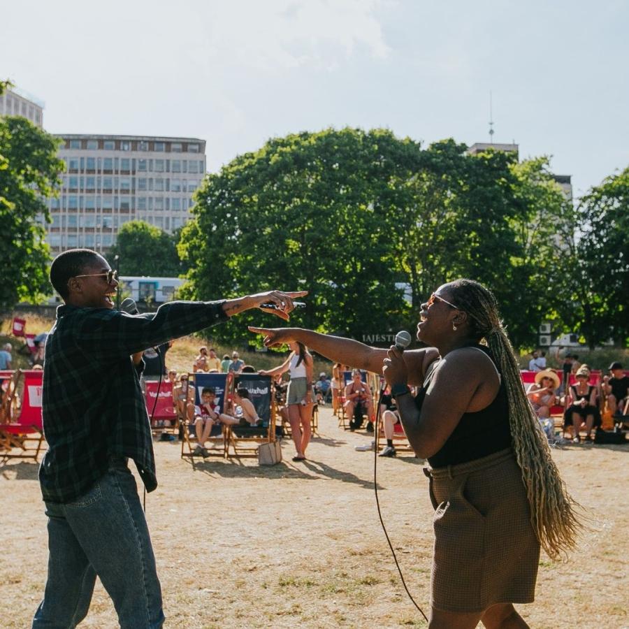 2 singers at Bearpit Karaoke facing each other & pointing while singing into microphones