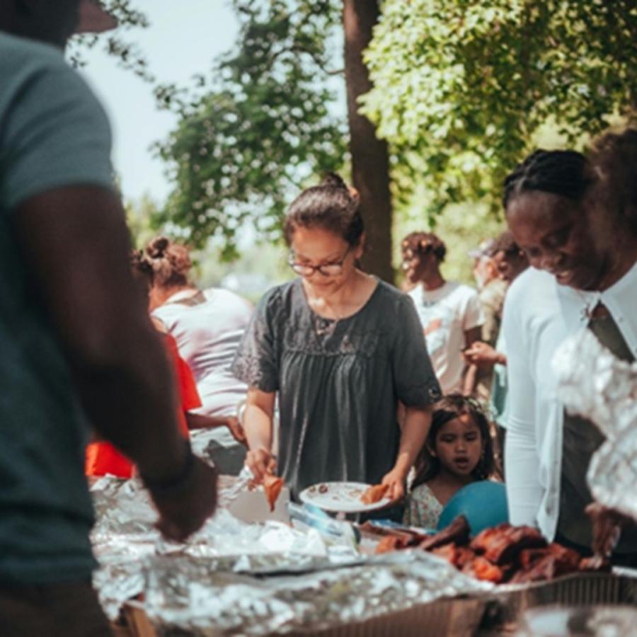 people at outdoor table serving themselves food