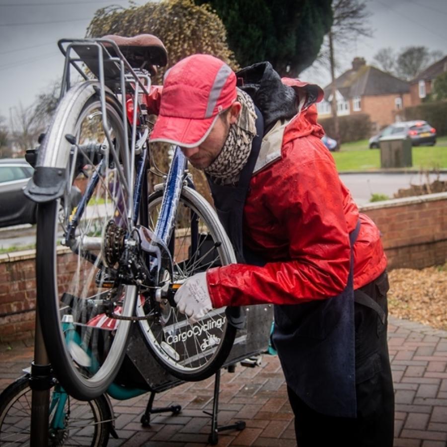 bicycle repair by man in red baseball cap