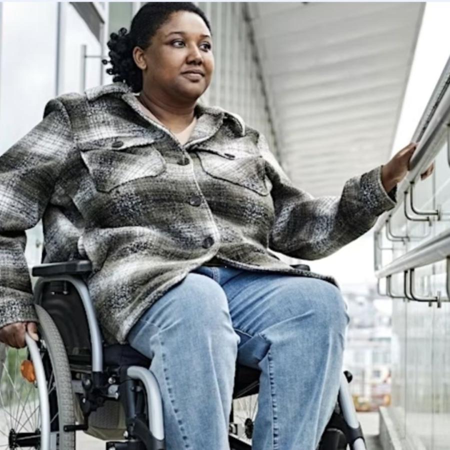 library photo of woman in check shirt using wheelchair