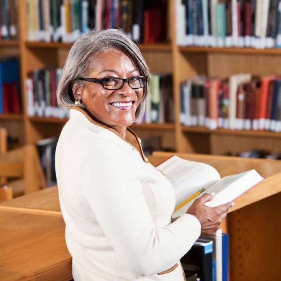 A woman standing in a library, posing in front of a camera