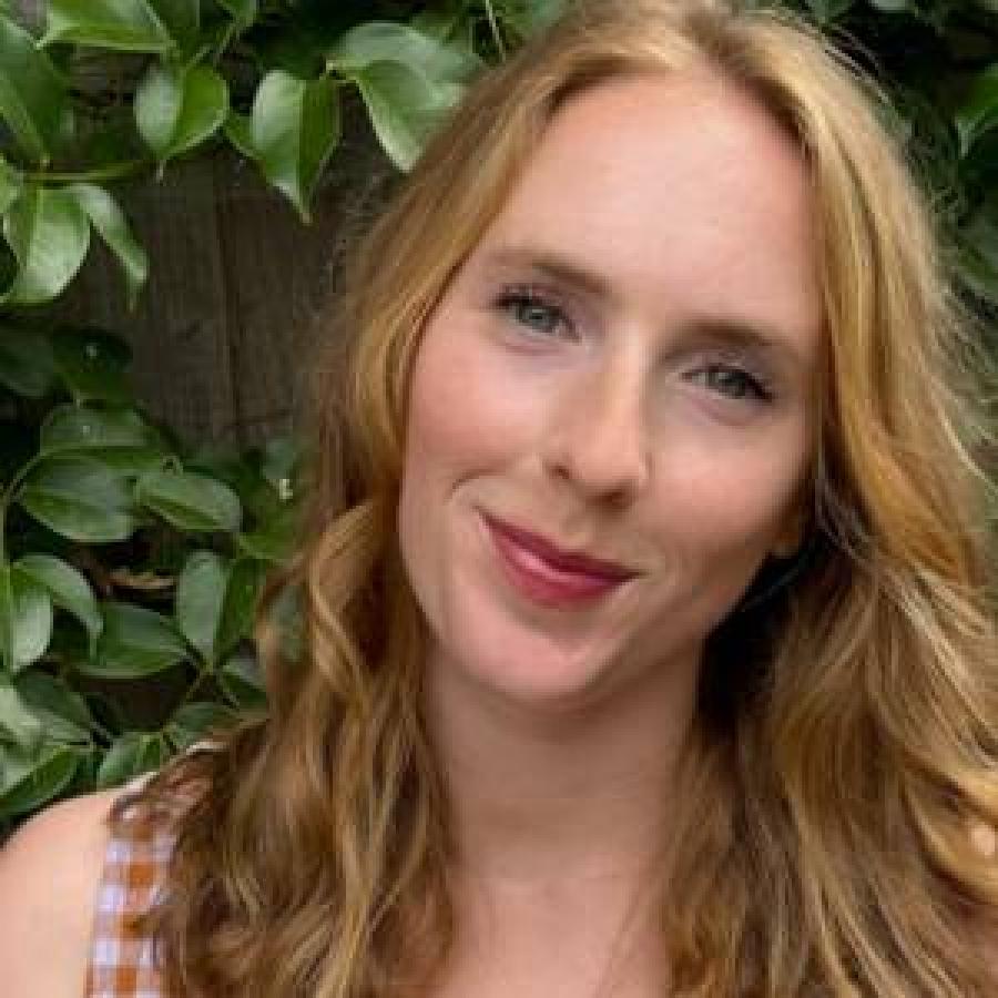 A photo of Celia standing beside a tree, posing and smiling at the camera