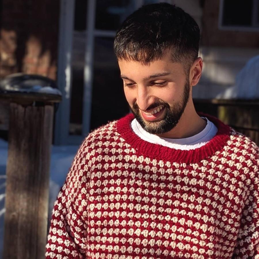 A photo of Lucas Fothergill looking at the floor with a warm, thoughtful smile.