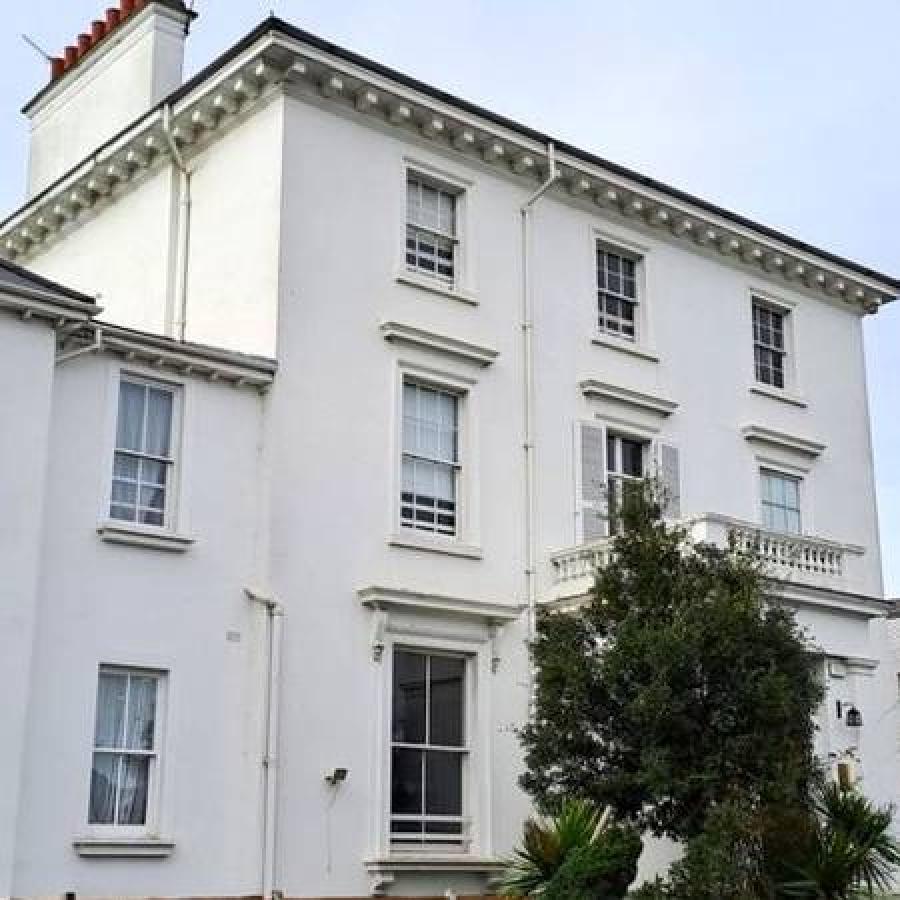 Elegant white townhouse with tall windows, balcony, and classic architectural detailing.
