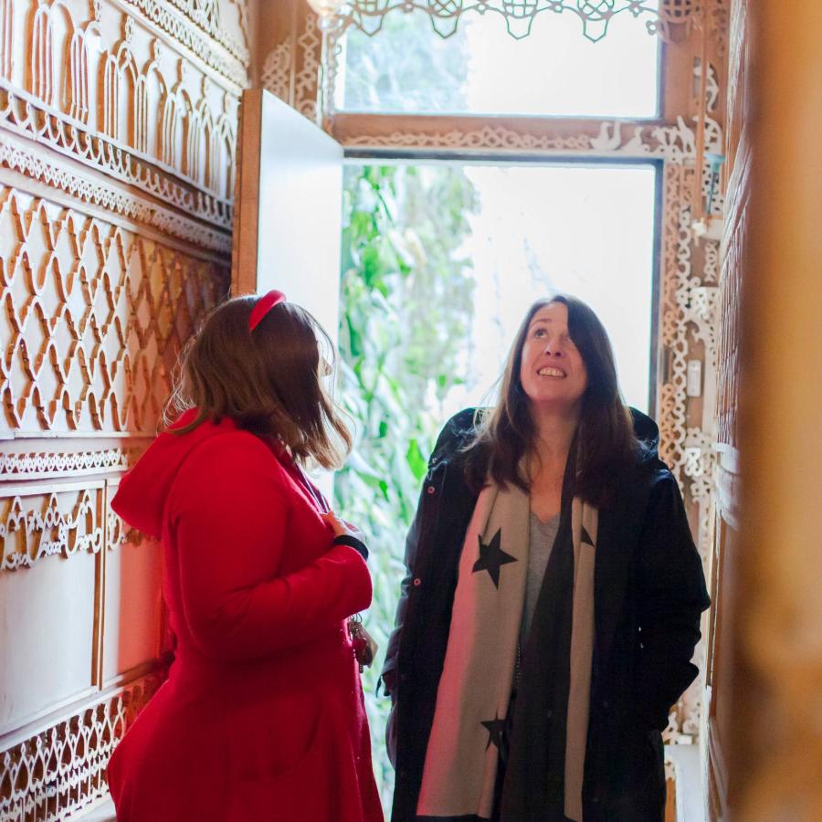 Two people admire ornate interior beside bright doorway, illuminated daylight.