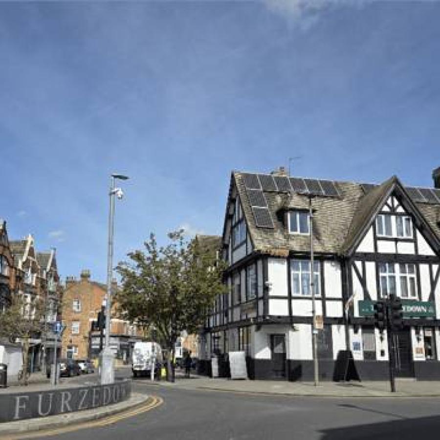 Timber-framed corner building with solar panels on a bright urban street.