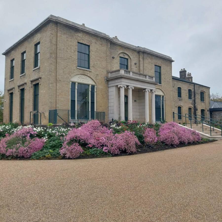 Elegant brick manor framed by pink blossoms and curved walkway